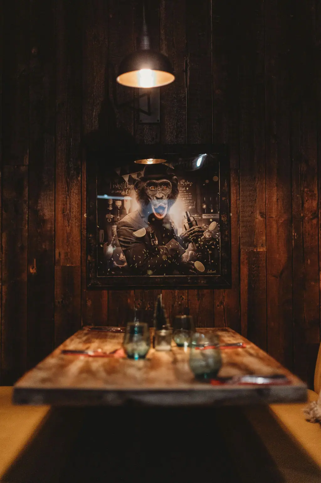 A booth table set beneath the monkey bartender portrait