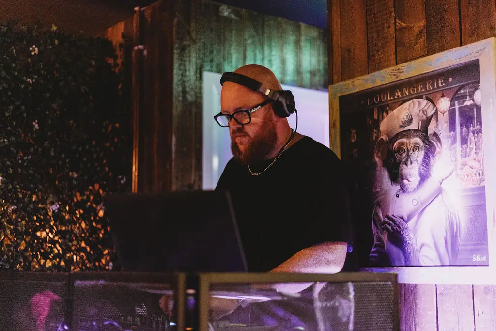 The resident DJ mixing behind the decks at The Teal Monkey