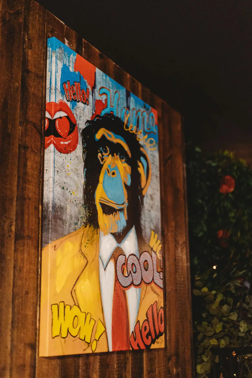 Pop-art painting of a monkey in a yellow suit with Hello, Wow and Cool lettering