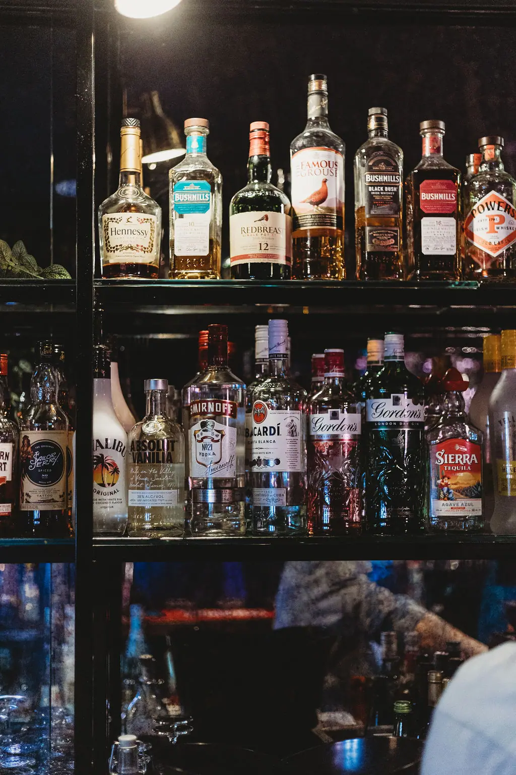Back-bar shelves of whiskey, gin, rum and vodka bottles