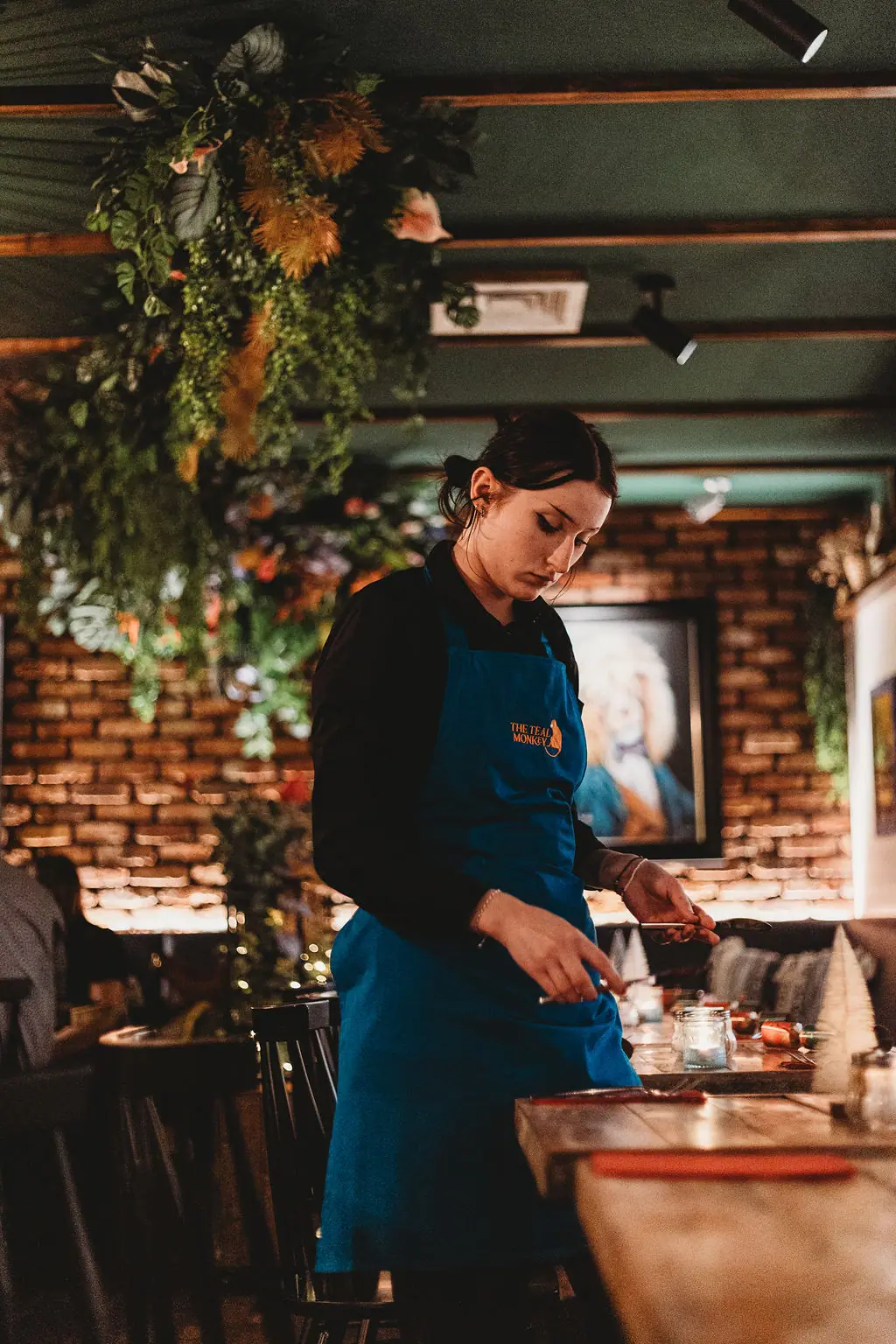 A member of the Teal Monkey team in a teal apron setting a table
